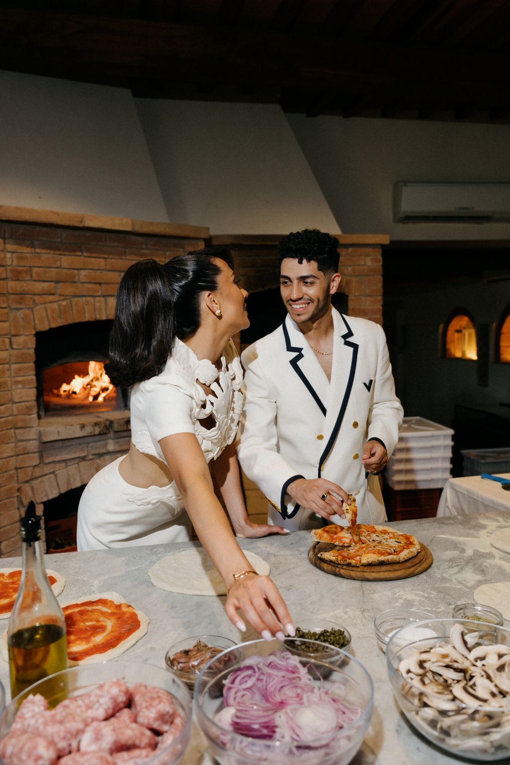 Image may contain Mena Massoud Adult Person Wedding Desk Furniture Table Food Pizza Meal Fireplace and Indoors