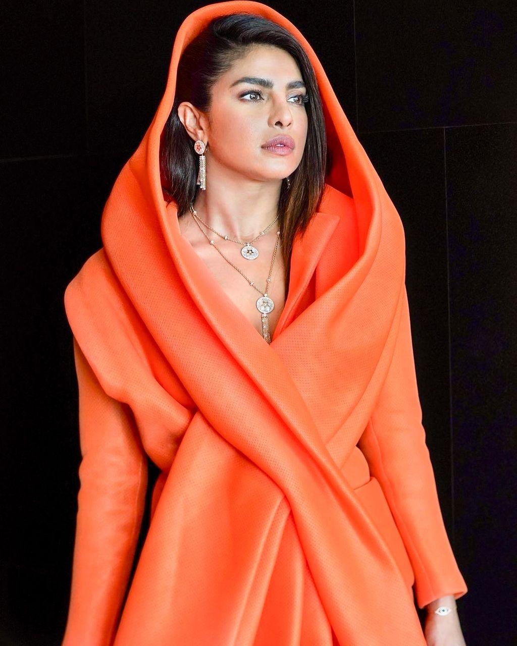 Priyanka Chopra wore an orange blazer dress with a draped shawl cape from DutchMoroccan designer Mohamed Benchellal's...